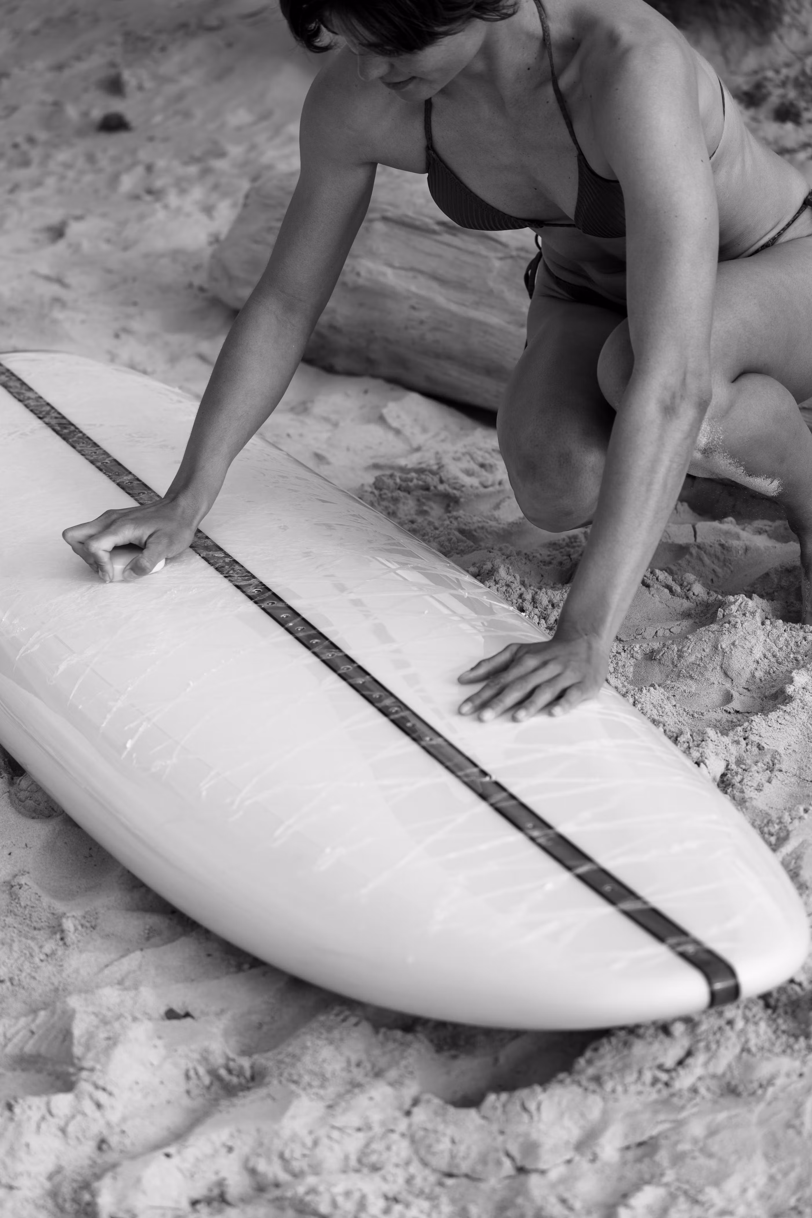 Woman inspecting the nose of a LIND electric surfboard on the beach