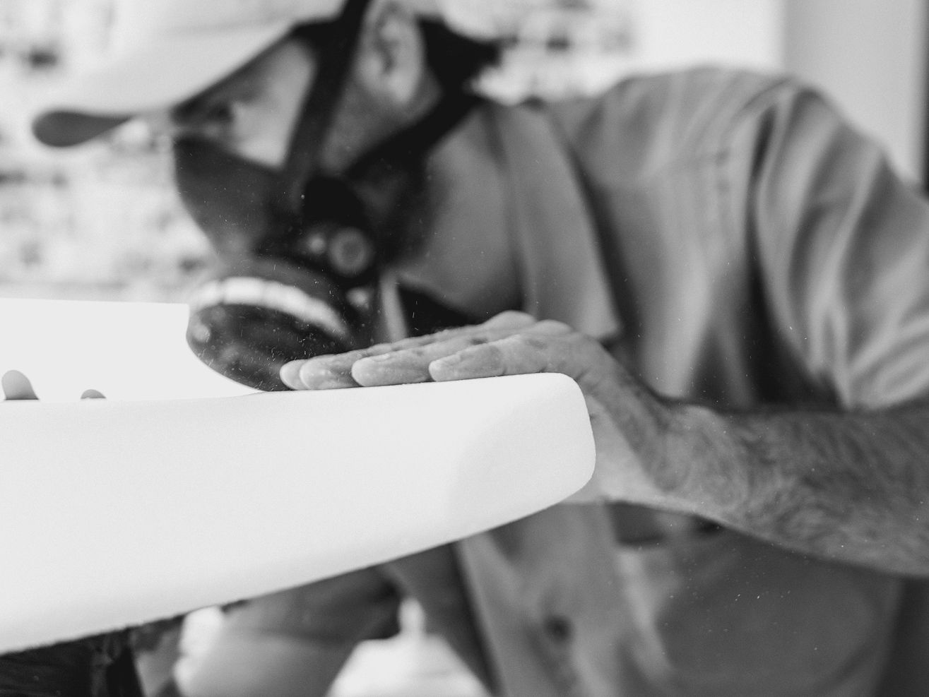 Shaper sanding the rail of a LIND electric surfboard during crafting